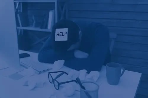 Frustrated employee at cluttered desk with “HELP” note, symbolizing accounting ERP system challenges and data silos.